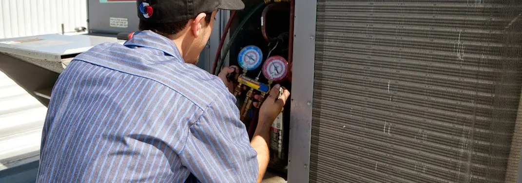 HVAC technician servicing a condenser unit in Finneytown